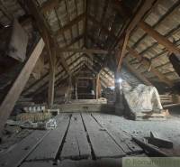 Attic storage space of a family house with wooden beams and a layer of dust.