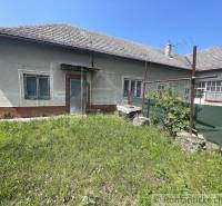 The back part of a family house in Nové Zámky with a grassy yard and older equipment.