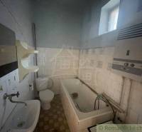 A bathroom in a family house with a bathtub, sink, toilet, and water heater.
