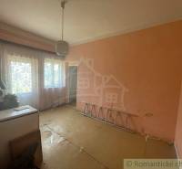 A room in a family house with orange walls, curtains, and white furniture.