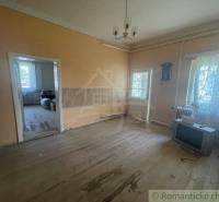 A spacious living room in a family house with wooden flooring and an older television.
