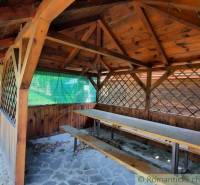 A wooden pergola at the cottage in Malé Kozmálovce with a long bench and a table.