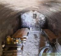 Stone cellar in a cottage with wooden benches and canned goods for storage.