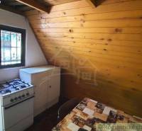 Rustic kitchen in a cottage with a gas stove and wooden paneling.