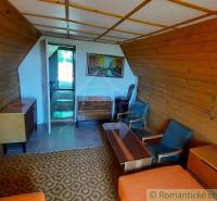 A wooden interior of a cabin with a carpet pattern, furniture, and a painting on the wall.