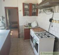 A family house kitchen with a gas stove and a window with blinds.