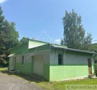 A family house in Poltár with a flat roof surrounded by nature and trees.