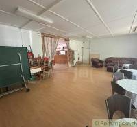 A large room with sofas, tables, chairs, and a curtain in a family house.