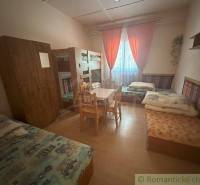 A room with a bunk bed, separate beds, a table, and a wardrobe in a family house.