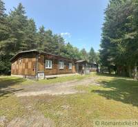 A family house in Poltár with a garden surrounded by forest and coniferous trees.
