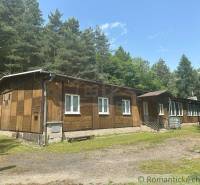 The exterior of a family house surrounded by a forest in Poltár under a blue sky.