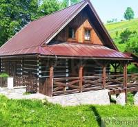 A wooden cottage in Kežmarok surrounded by greenery and trees, ideal for relaxation.