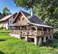 A wooden cottage near Kežmarok surrounded by greenery and deciduous trees.