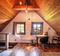 Attic room in a wooden cabin with a desk, chair, and window.