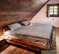 Attic bedroom with a wooden bed and a window in a cozy cabin.