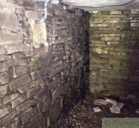 Stone walls in the interior of the cabin with exposed piping on the ceiling.