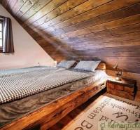 Wooden bedroom in a cabin with a double bed and a decorative rug.