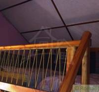 Attic in a cottage with wooden railing, bed, and television.