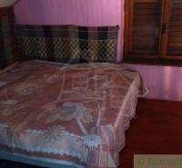 A bedroom in a cottage with a wooden bed and pink walls, feels cozy.