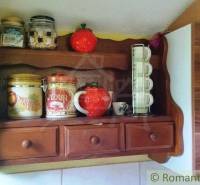 Wooden shelf with jars and cups in the cottage. Cheerful kitchen atmosphere.