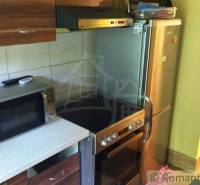 A kitchen in a cottage with a microwave, electric kettle, and stove, next to a refrigerator.