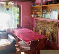The interior of the cottage with pink walls, a dining table, and a sofa creates a cozy atmosphere.
