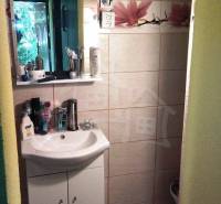 A bathroom in a cottage with a sink, a mirror, and decorative tiles with a floral pattern.