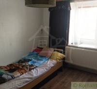 A simple room with a bed, a window, and curtains in a family house.