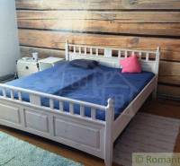 Bedroom in a family house with a wooden wall and a white bed.