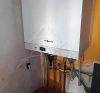 Viessmann boiler in a family house; white unit on an orange wall with piping.