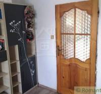 Wooden door in a family house, next to it a shelf with books and decorations.