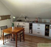 Kitchen area of a family house with a window, table, and white cabinets.