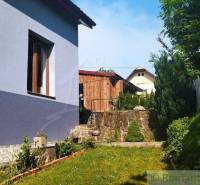 A garden of a family house in Spišská Nová Ves with a wooden cottage and greenery.