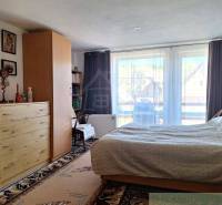 A bright bedroom in a family house with wooden furniture and a view through French windows.