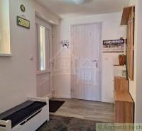 Interior of a family house with an entrance door, a bench, and a coat rack.