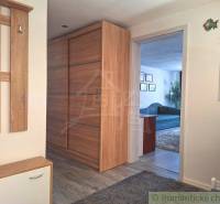A hallway in a family house with wooden furniture, a coat rack, and a view into the living room.
