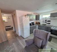 A kitchen in a family house with furniture, appliances, and a chair in a bright space.