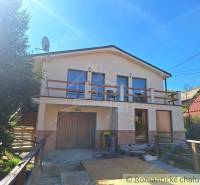 A family house in Liptovský Mikuláš with a balcony and a garage, surrounded by greenery.