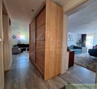 A hallway in a family house with a wooden wardrobe and a living room with a sofa.