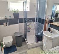 A bathroom in a family house with a glass shower enclosure and comfortable amenities.