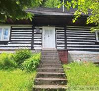 A traditional wooden family house in Ružomberok surrounded by greenery and flowers.
