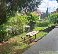 A garden with a bench and a table by a family house in Ružomberok, surrounded by greenery.