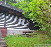 A family house in Ružomberok with a wooden facade and an outdoor seating area surrounded by greenery.