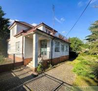 A family house in Plavecký Štvrtok with a white facade and a large garden in summer weather.