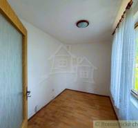 An empty room in a family house with wooden doors and a large window with a curtain.