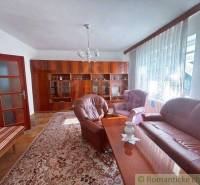A living room in a family house with brown furniture and pink upholstered seating.