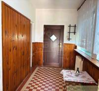 A hallway in a family house with wooden paneling and a tiled floor.