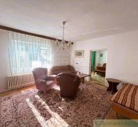 Living room of a family house with comfortable armchairs, a sofa, and a large carpet.