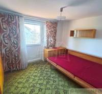 A bedroom in a family house with a bed, a cabinet, and decorative curtains.