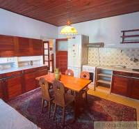A kitchen in a family house with a wooden ceiling, retro furniture, and patterned tiles.